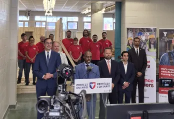A group of people including Trevor McAlmont, Minister Piccini, and YMCA Power of Trades staff standing in front of a camera.