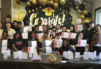 The graduating class of the YMCA's Culinary Training Program standing alongside program staff and holding their certificates