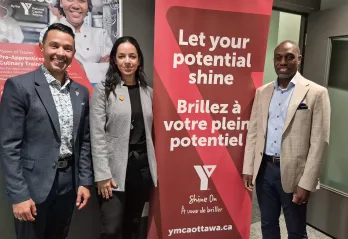 Morgan Bello, Audrey Joyal, and Trevor McAlmont posing next to a Y Shine On banner