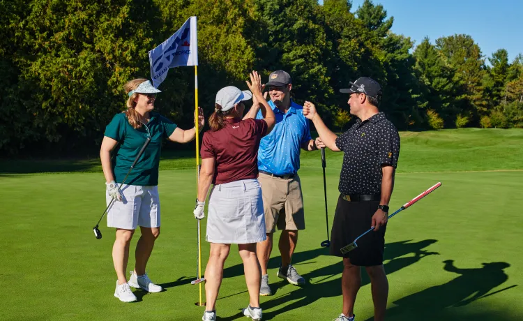 Four golfers high fiving on a golf course