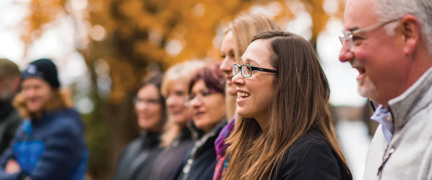 A group of adults standing outside in an autumn setting.