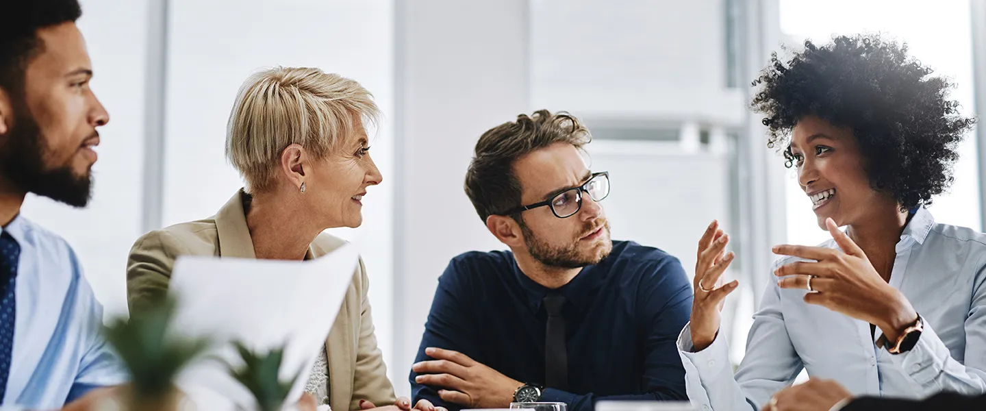 A diverse group of people sit around a table having a conversation.