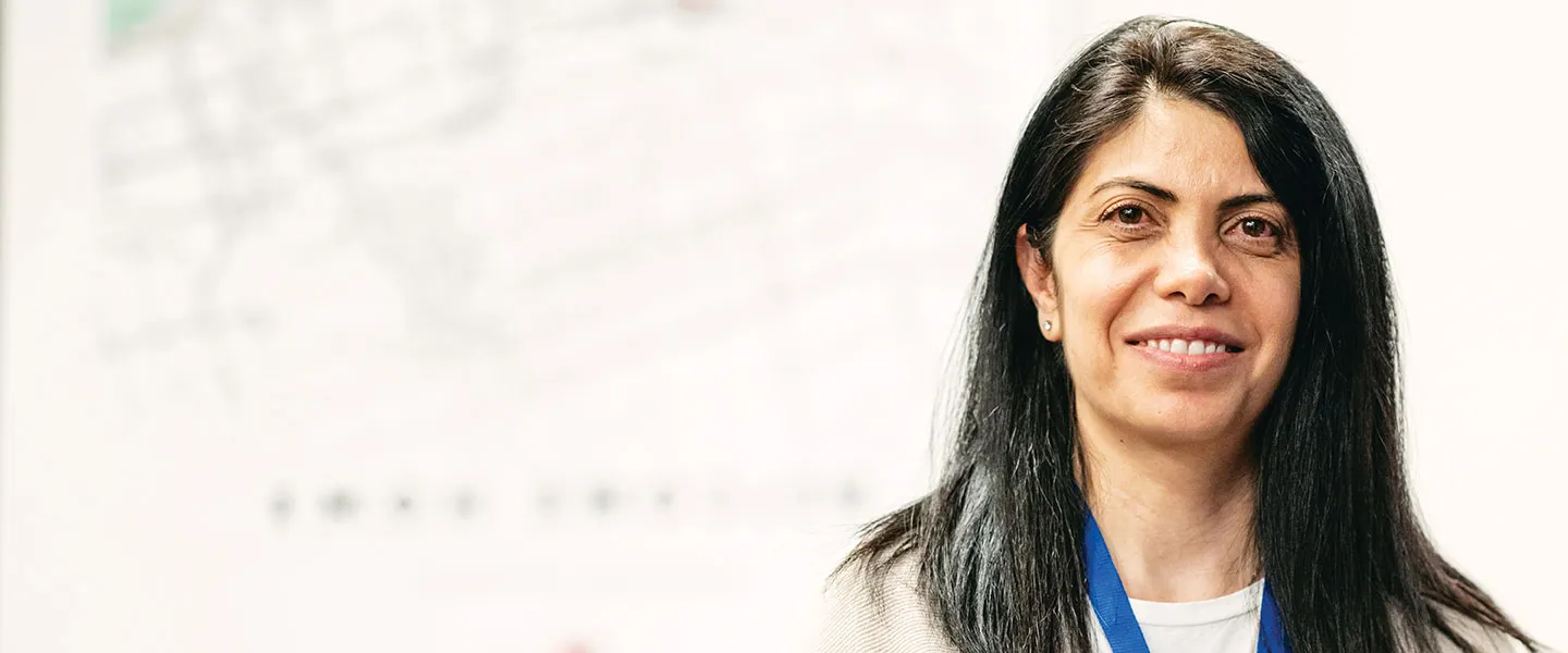 A woman with long black hair, smiling softly while facing the viewer.