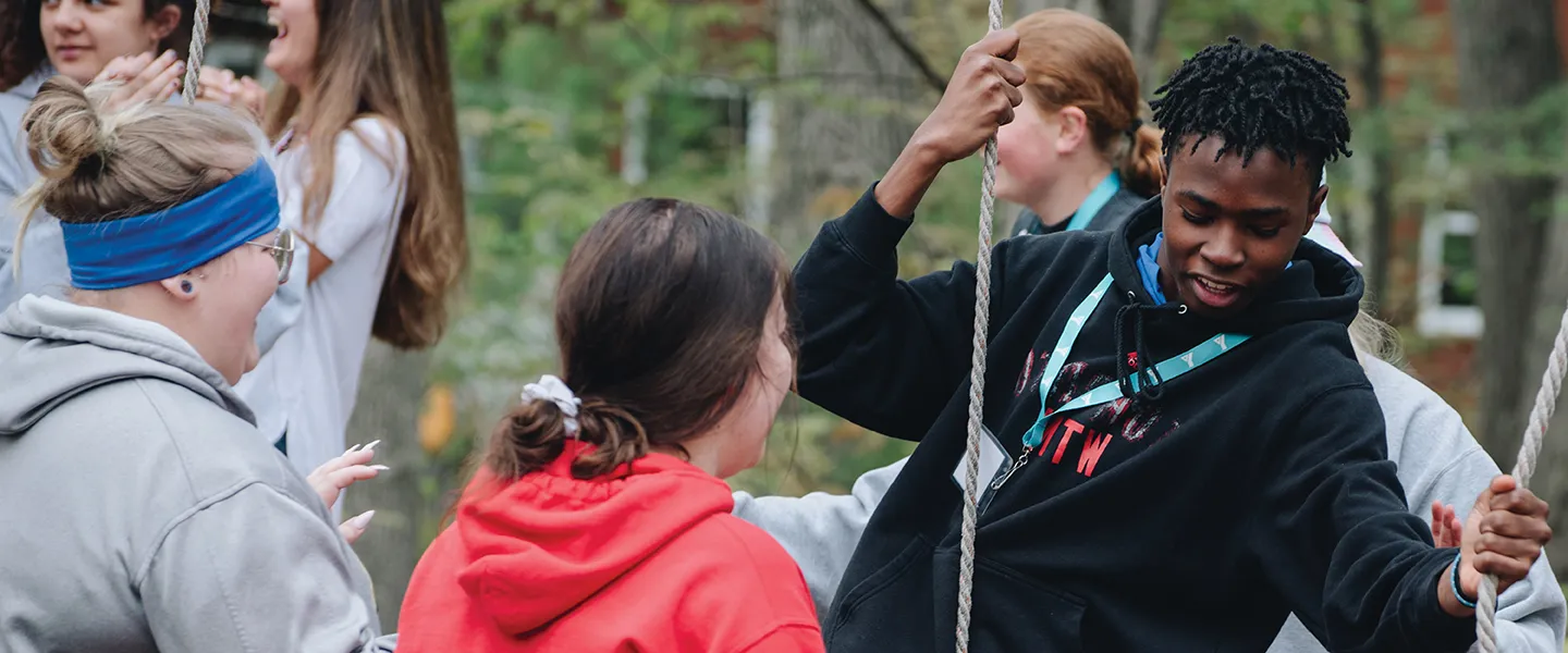 A team of people enthusiastically participating in a rope game, showcasing teamwork and fun in an open area.