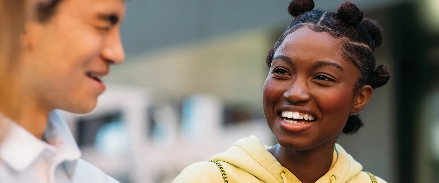 A young woman smiles while engaging in conversation.
