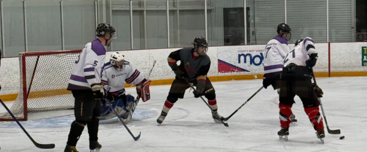 Hockey players approaching a net on an ice rink.