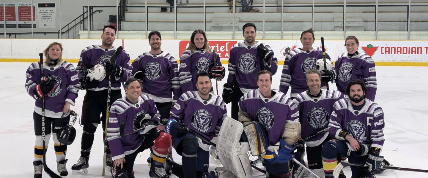Dentons Purple Cobras hockey team posing for a group photo on the ice