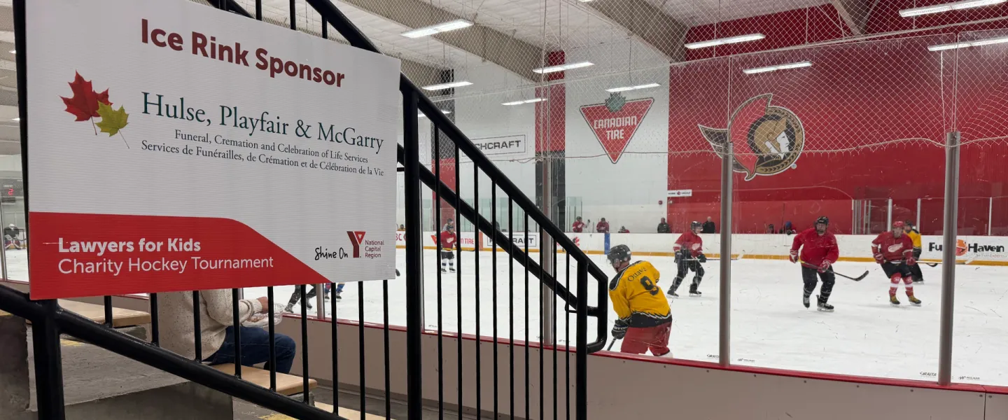 A sponsor sign on the side of the stands. Hockey players are on the ice rink.
