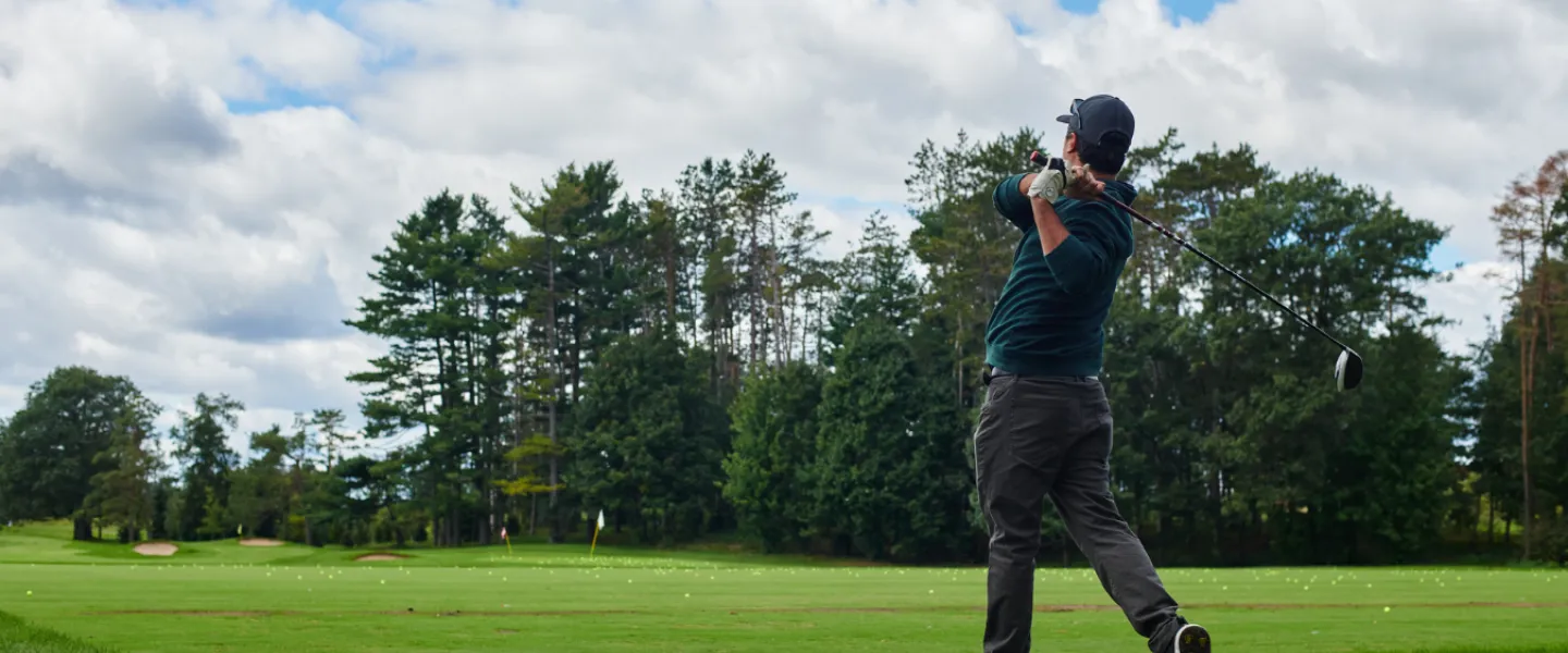 A golfer swinging his club on a course