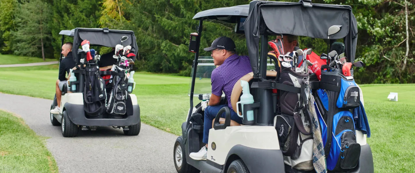 Golfers driving two golf carts down a path