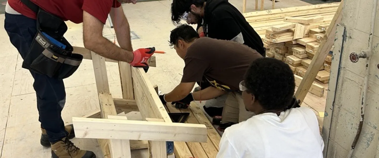 Skilled trades training program participants in a workshop, building a wooden bench