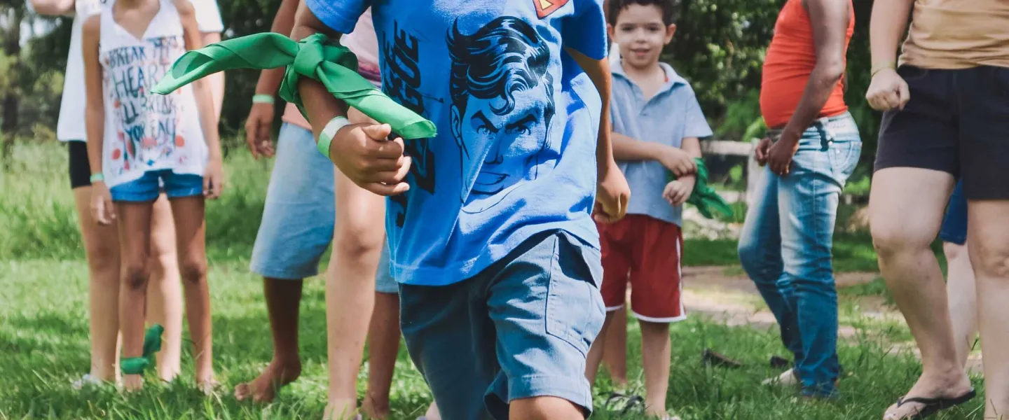 A child runs in the grass with families in the background