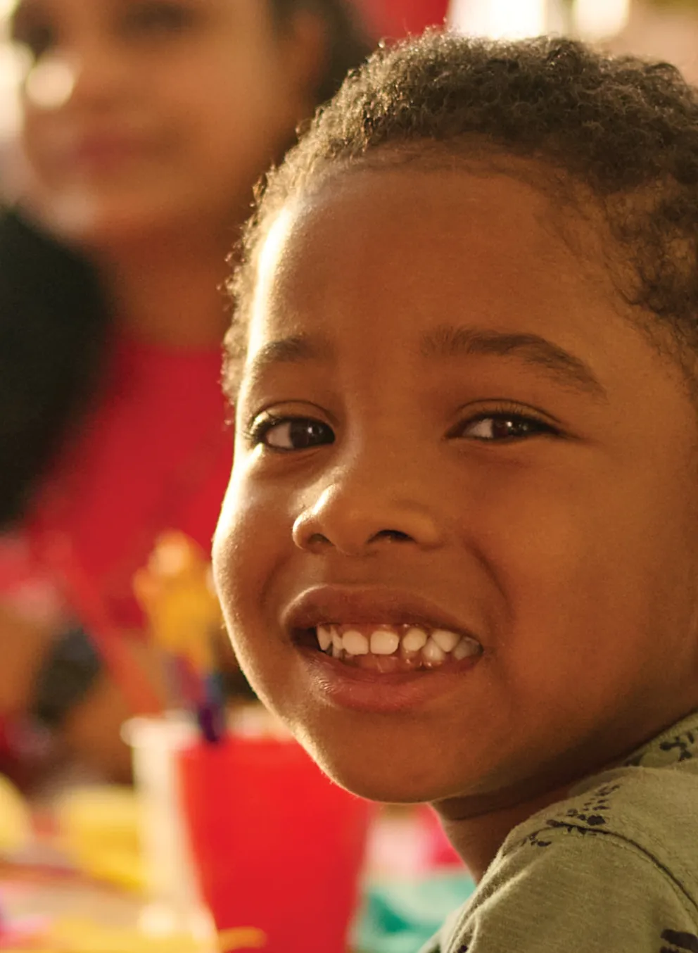 A happy child seated at a table with other children, all engaged in a joyful and friendly atmosphere.