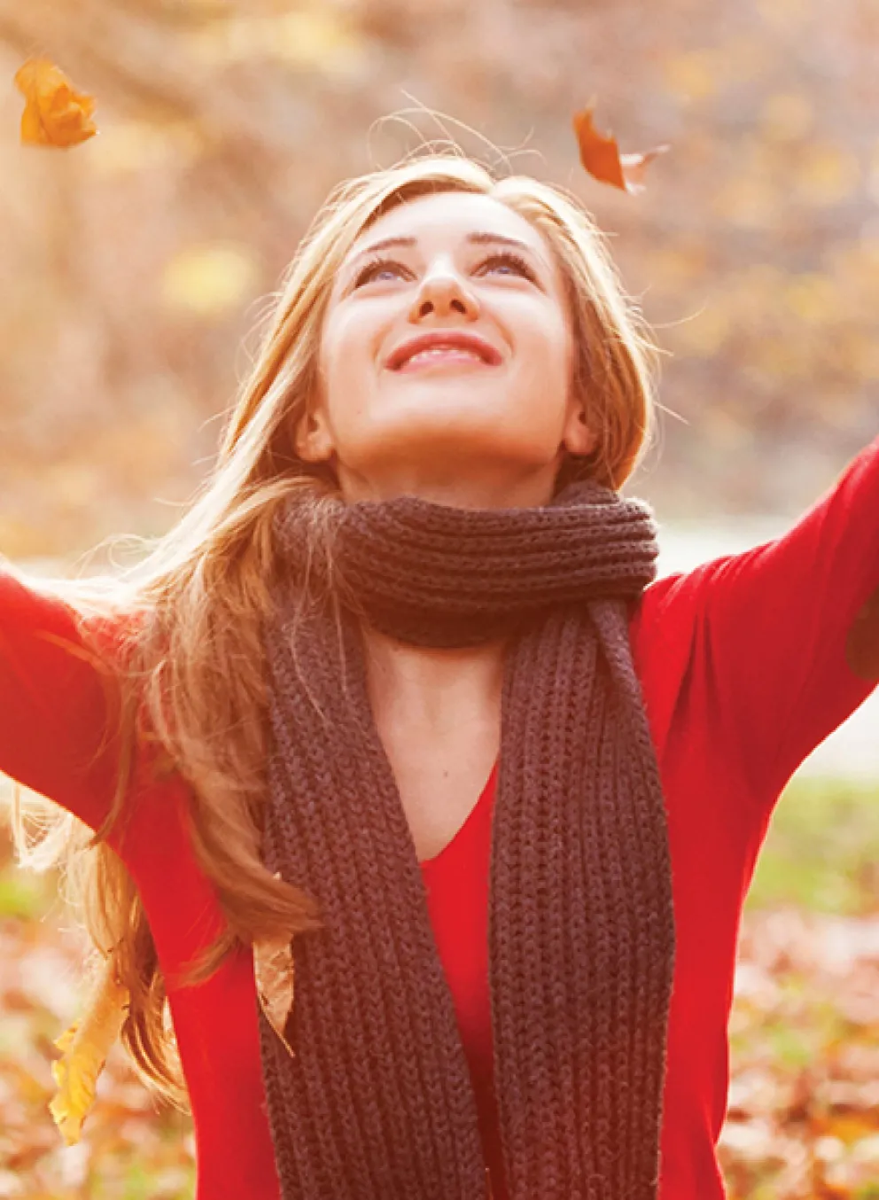 A woman in a red sweater raises her hands in the air, expressing joy.