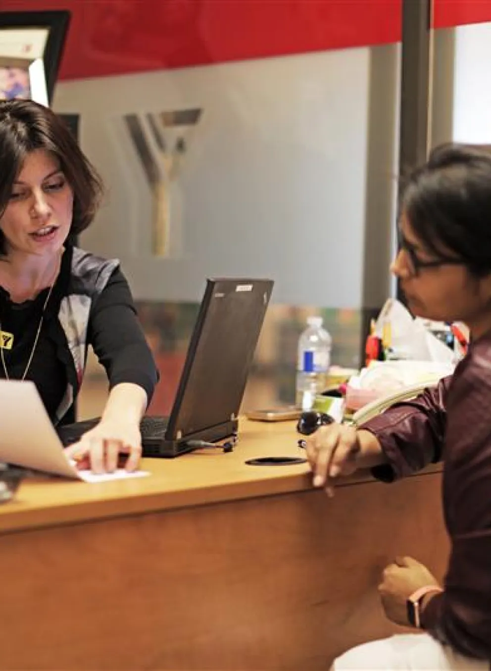 A Y staff member speaking to a client at a desk. They are looking at a piece of paper.