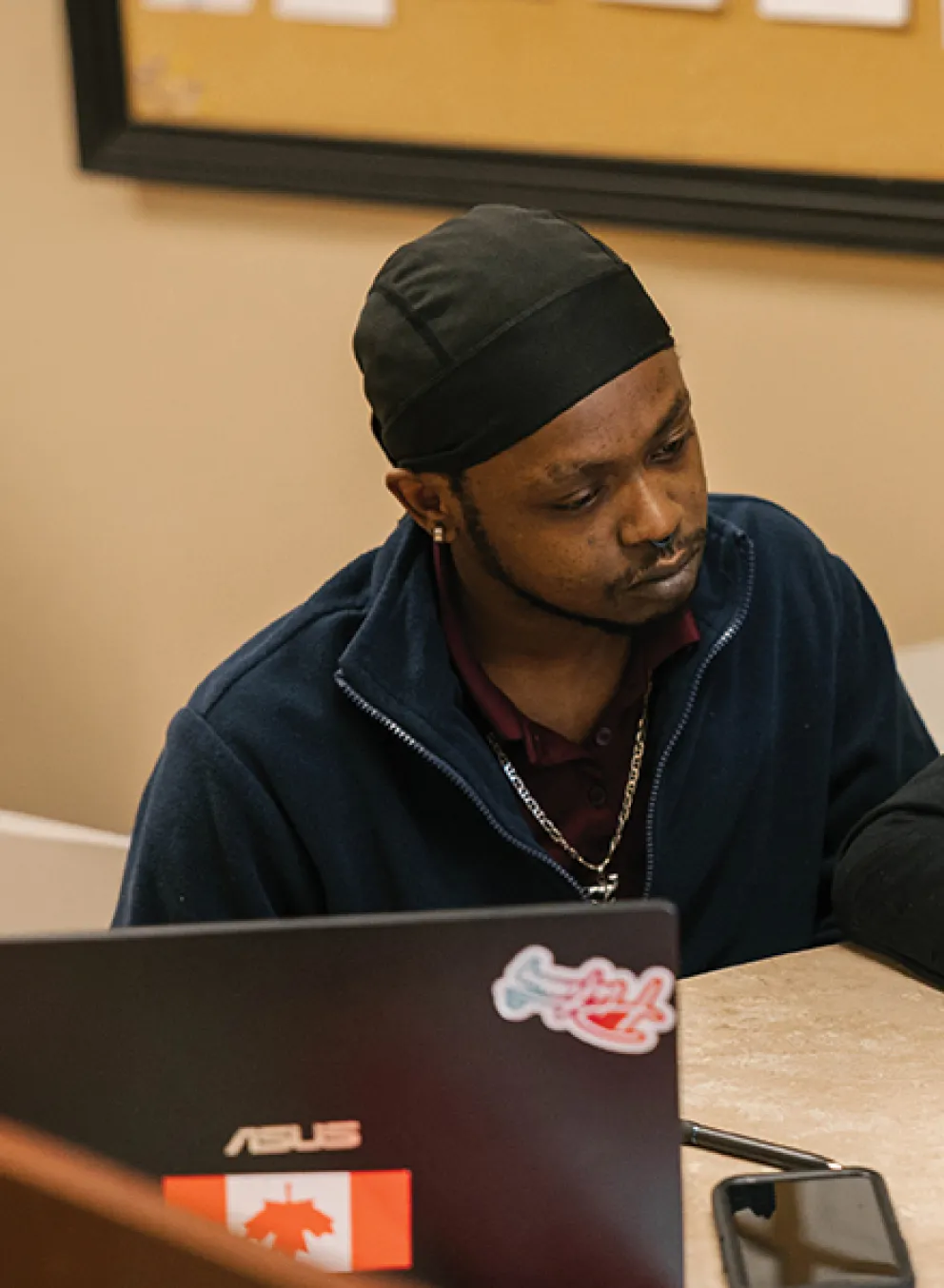Two individuals focused on their laptops while collaborating in a modern office setting.