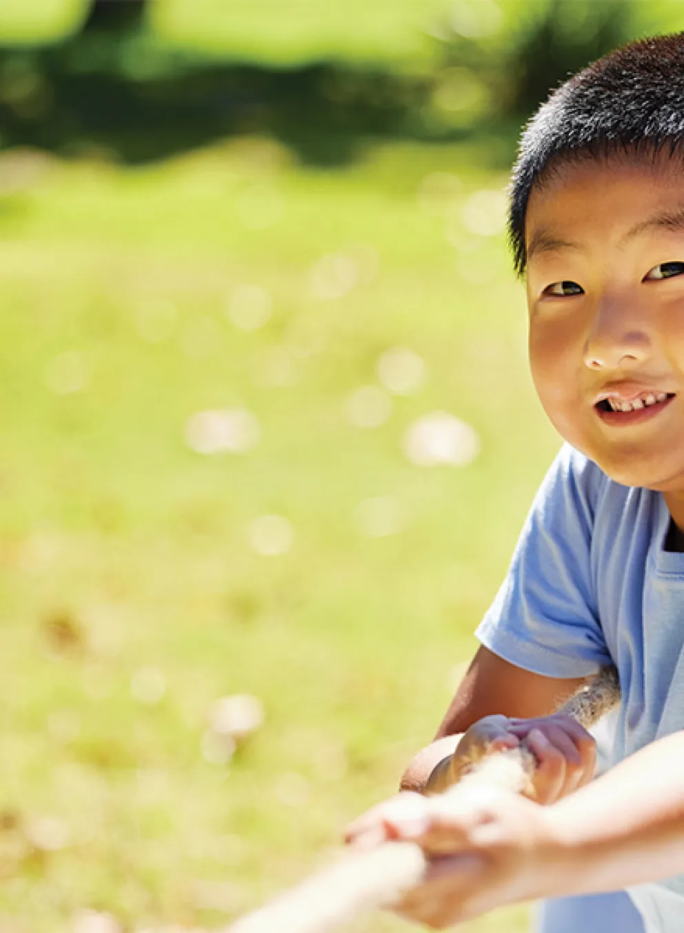 A cheerful boy stands in a vibrant field, smiling brightly as he enjoys the sunny day.