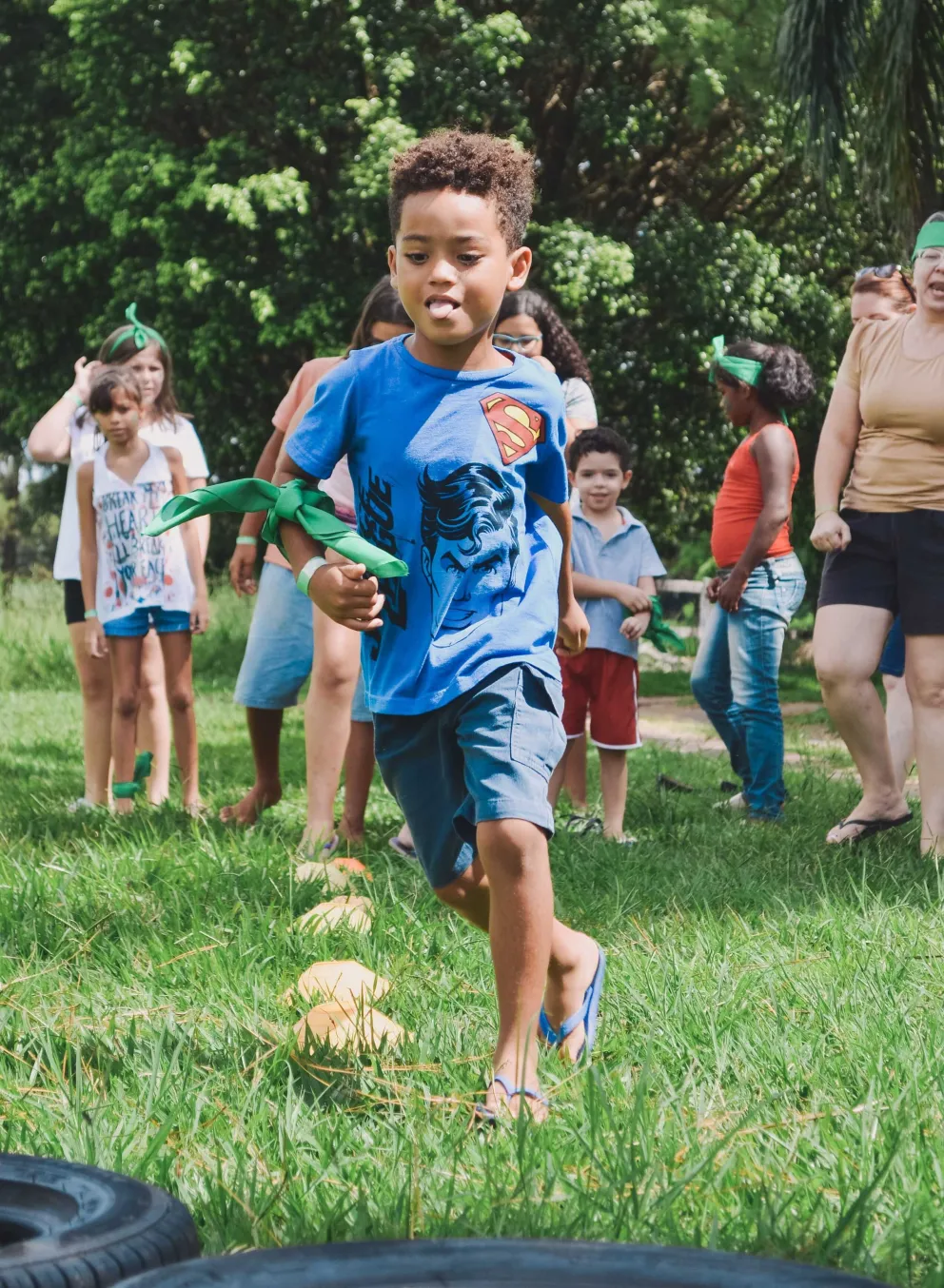 A child runs in the grass with families in the background
