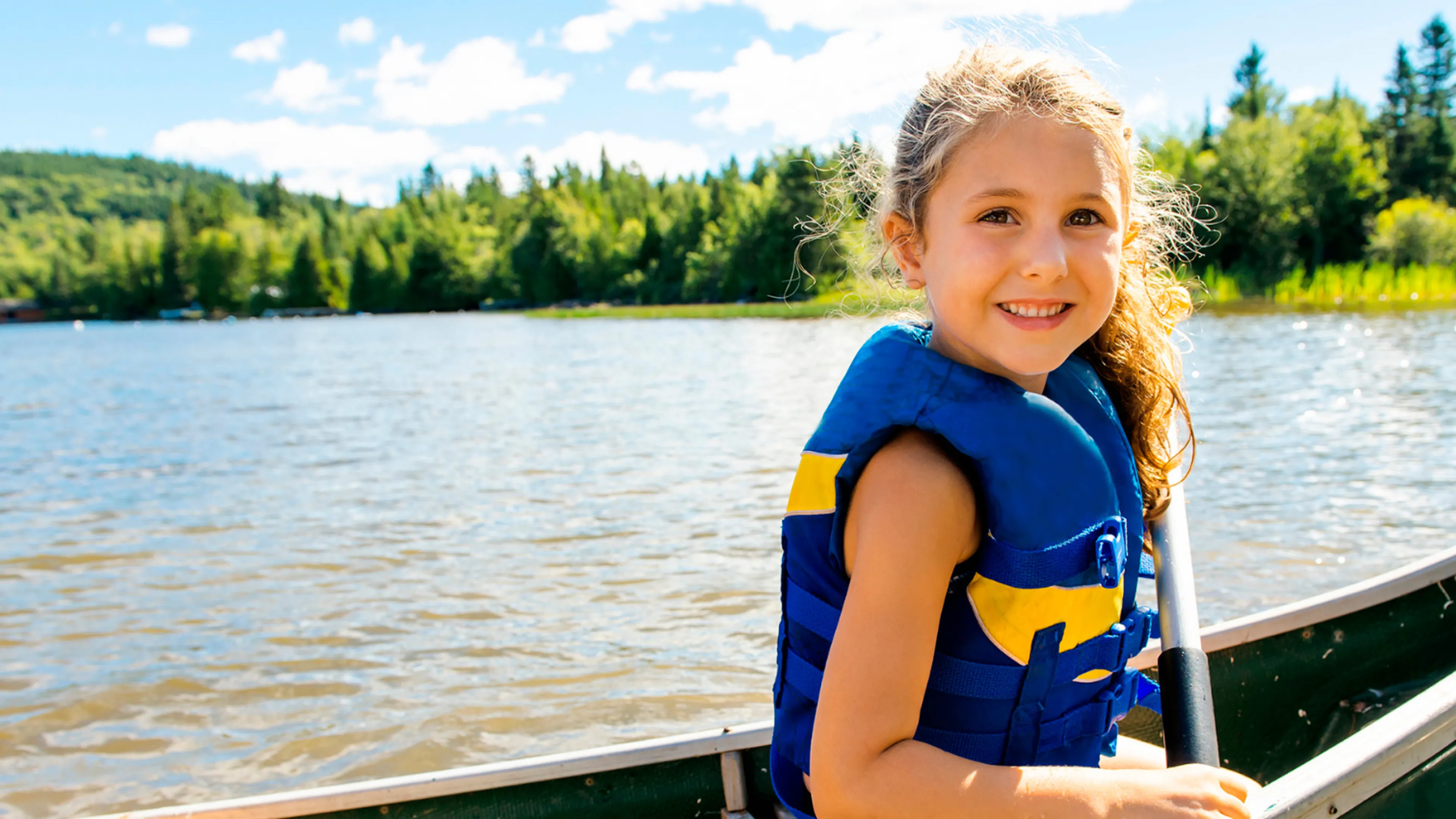 A girl wearing a lifejacket sits at the front of a canoe.