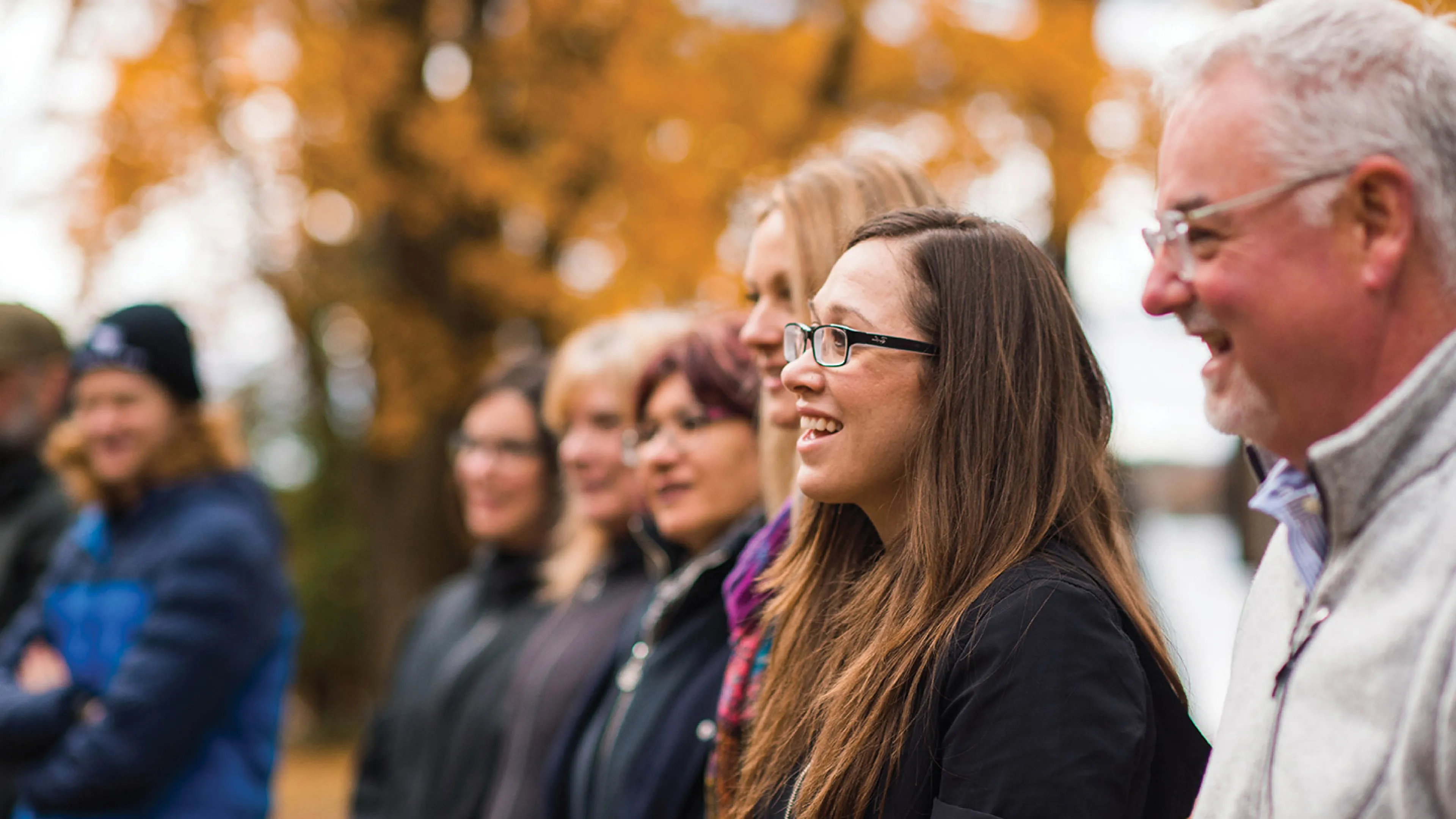 A group of adults standing outside in an autumn setting.