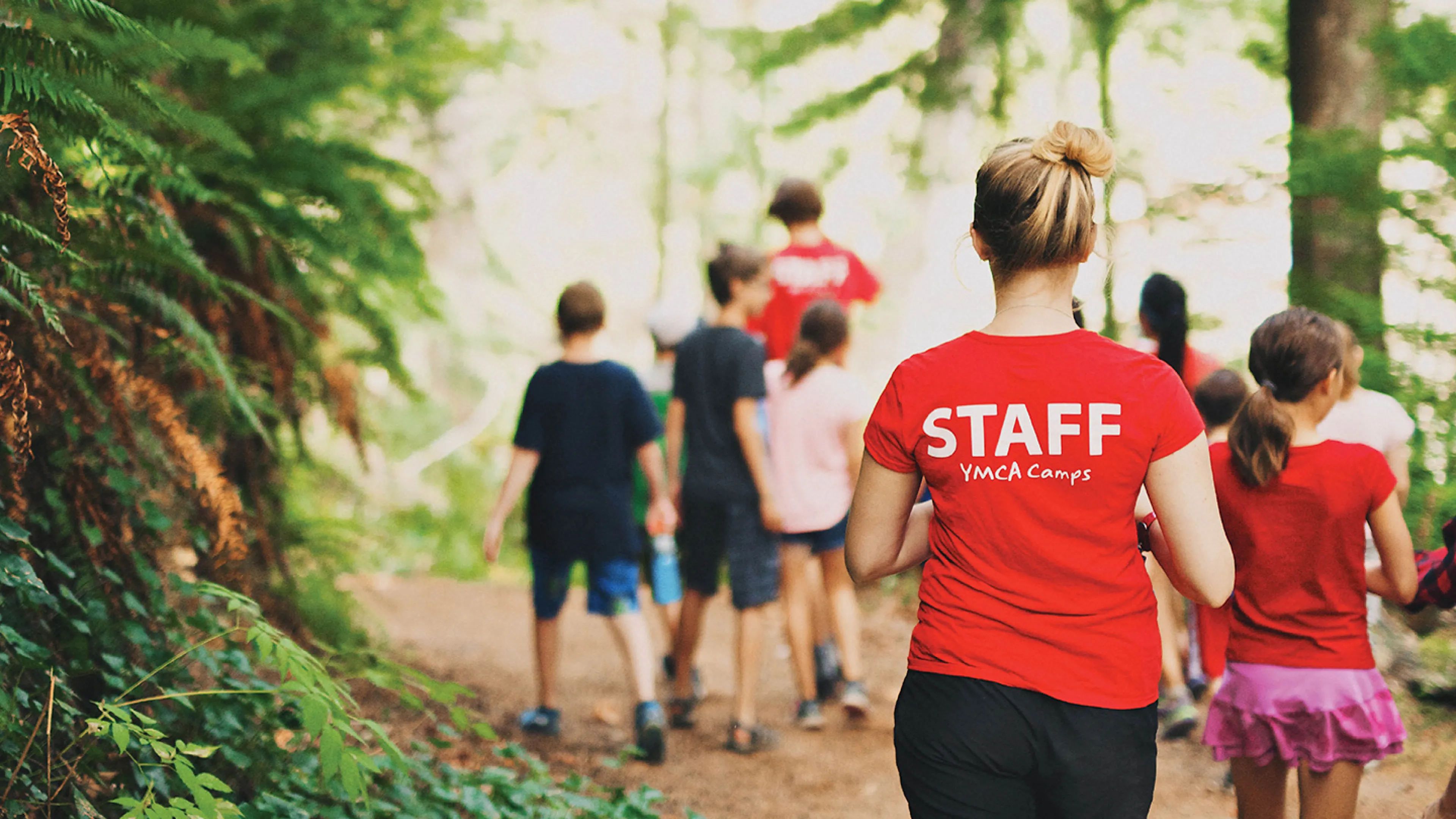 A group of children and camp counsellors walking down an outdoor path