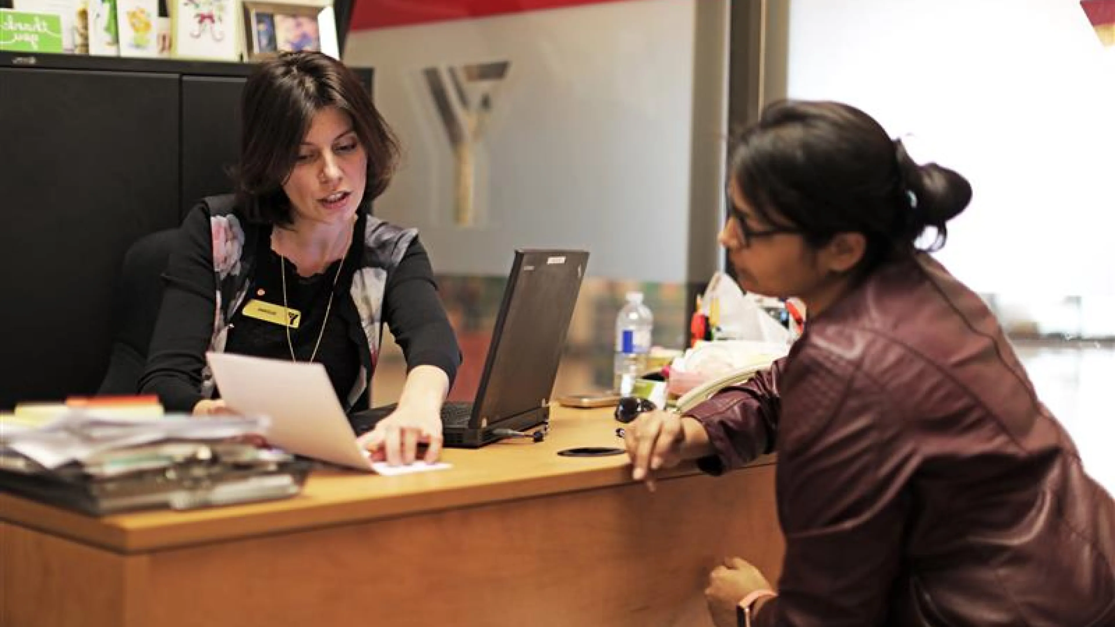 A Y staff member speaking to a client at a desk. They are looking at a piece of paper.