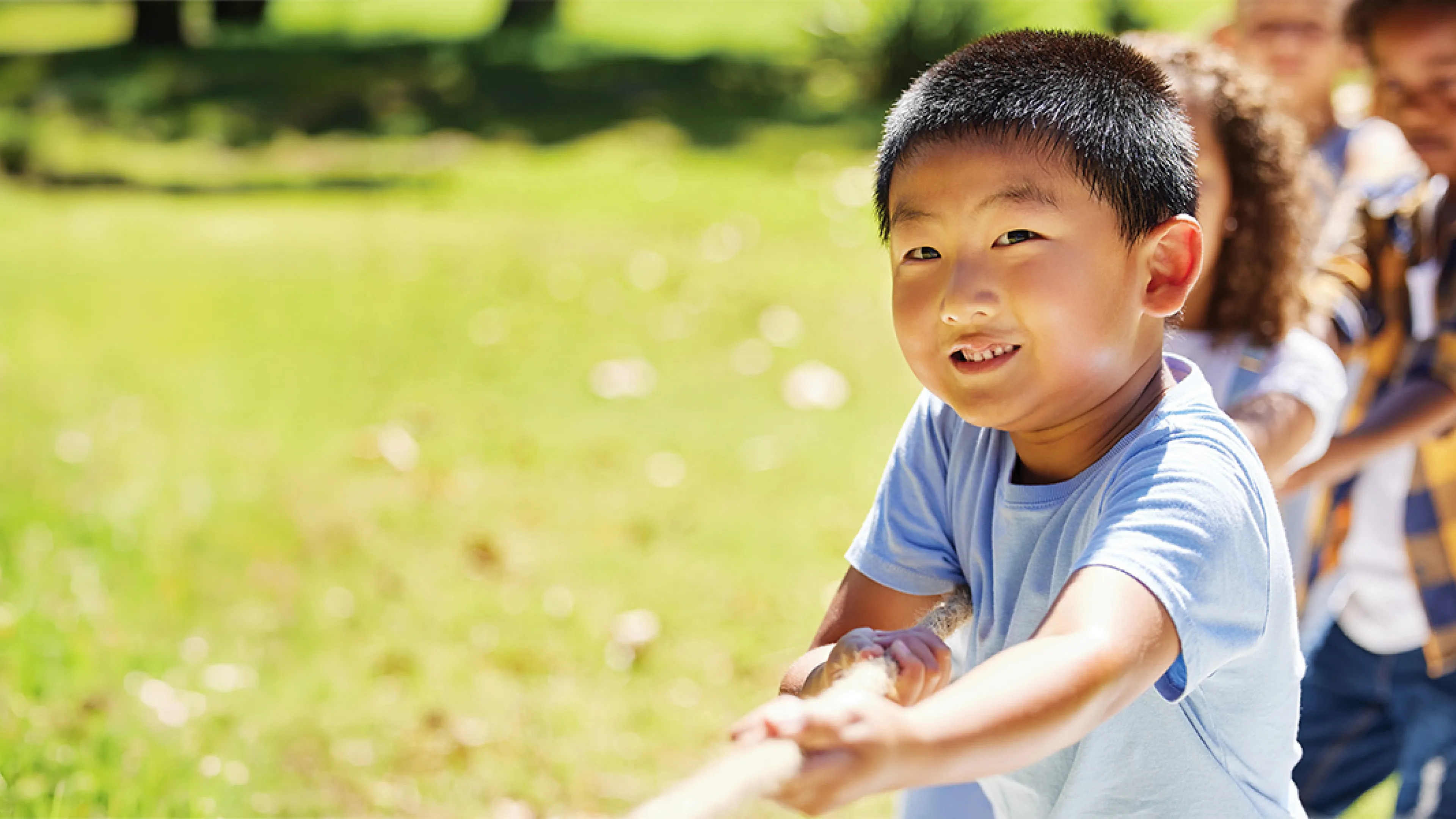 A cheerful boy stands in a vibrant field, smiling brightly as he enjoys the sunny day.