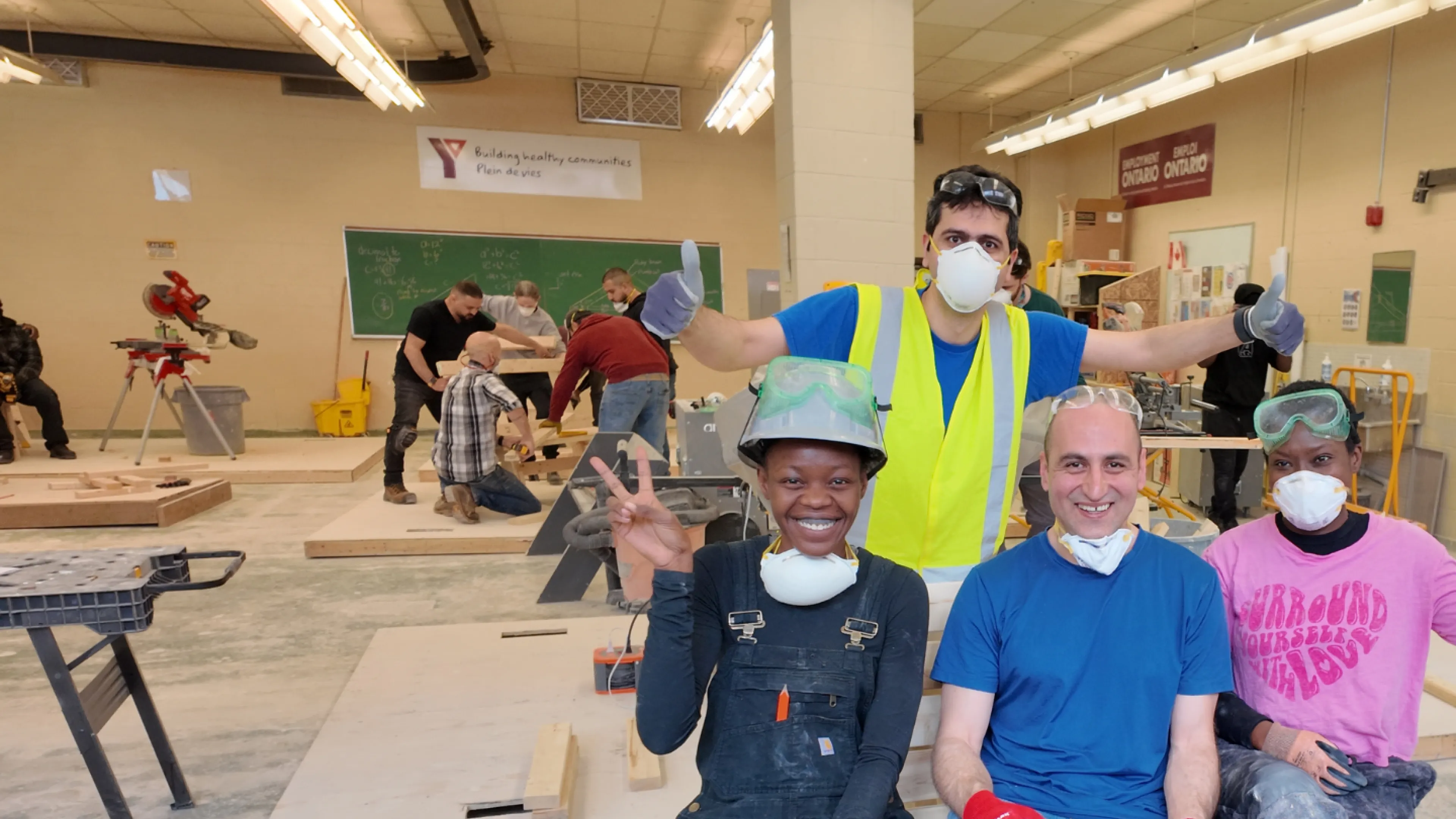 Four people posing for a group photo in a construction training workshop