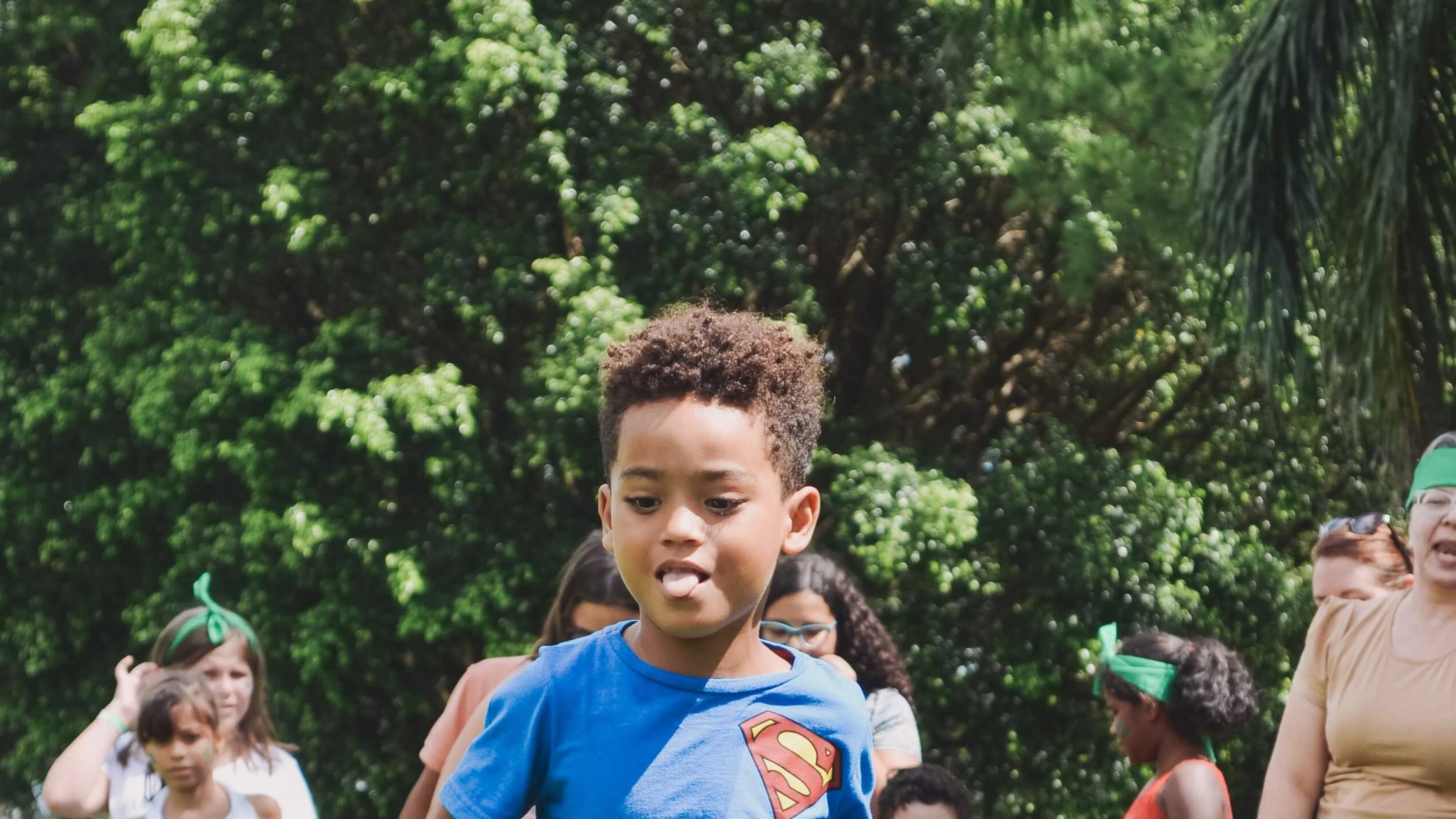 A child runs in the grass with families in the background