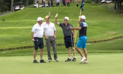 Four golfers on a golf course, two of them are high fiving