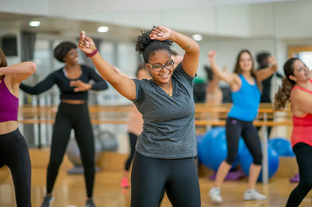 A diverse group of women enjoying a Zumba workout in a gym, moving in sync to upbeat music and vibrant choreography.