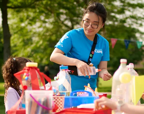 A woman in a blue YMCA Camp staff shirt poses for the photo, exuding a friendly demeanor.
