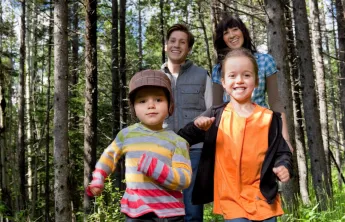 Two children and two parents walking through a forest