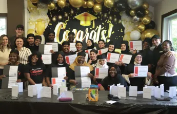 The graduating class of the YMCA's Culinary Training Program standing alongside program staff and holding their certificates