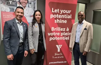 Morgan Bello, Audrey Joyal, and Trevor McAlmont posing next to a Y Shine On banner