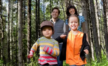 Two children and two parents walking through a forest