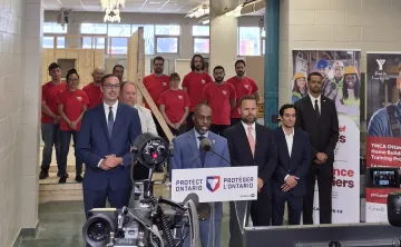 A group of people including Trevor McAlmont, Minister Piccini, and YMCA Power of Trades staff standing in front of a camera.